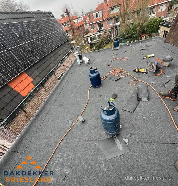 Daklekkage repareren met brandgereedschap op plat dak in Friesland