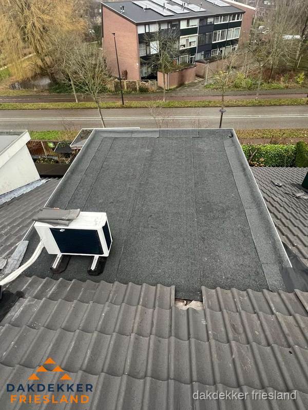 Plat dak inspectie met bitumen bedekking naast schuin pannendak in Friesland