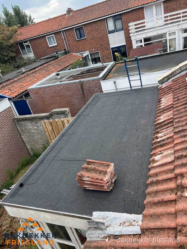 Plat dak aanbouw met bitumen naast schuin pannendak in Friesland