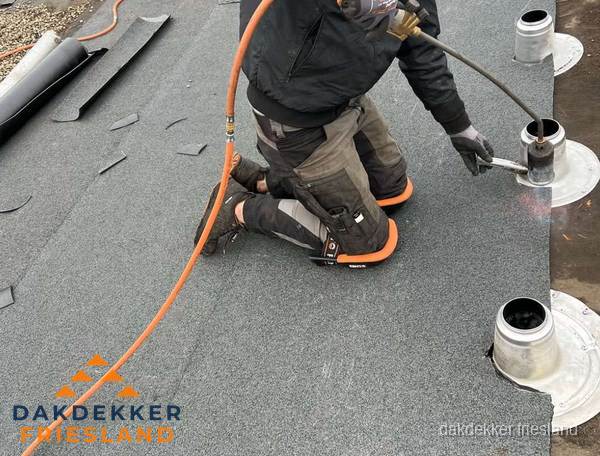 Dakdekker repareert bitumen dakleer bij dakdoorvoer in Friesland