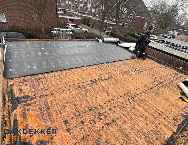 Dakdekker legt onderlaag op plat dak met houten constructie in Friesland